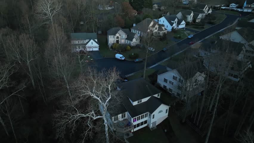 Luxury villas in American suburb neighborhood during sunrise. Leafless trees in fall season. Aerial approaching top down shot.