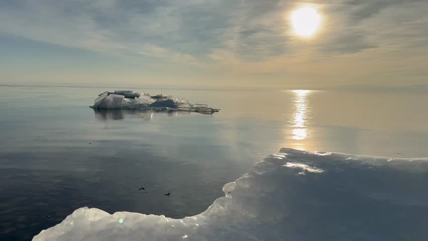 Video of beautiful landscape of Baikal Lake in January morning during freeze-up. Icy beach on frosty calm sunrise with reflection clouds on blue water. Scenic sea natural background. Winter travels 
