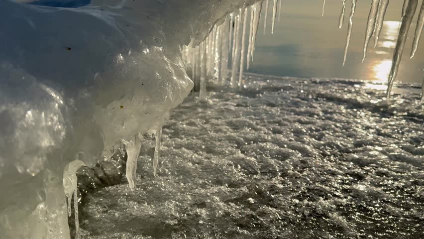 Video of Baikal Lake coast on January morning. Ice arch with icicles on icy beach during freeze-up of lake on sunrise. Beautiful unusual winter landscape. Changing seasons, natural phenomena 