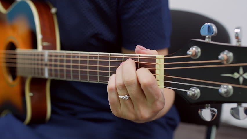 Close up of female hands skillfully playing an acoustic guitar, passionately practicing chords and creating beautiful melodies, showcasing talent and dedication to music