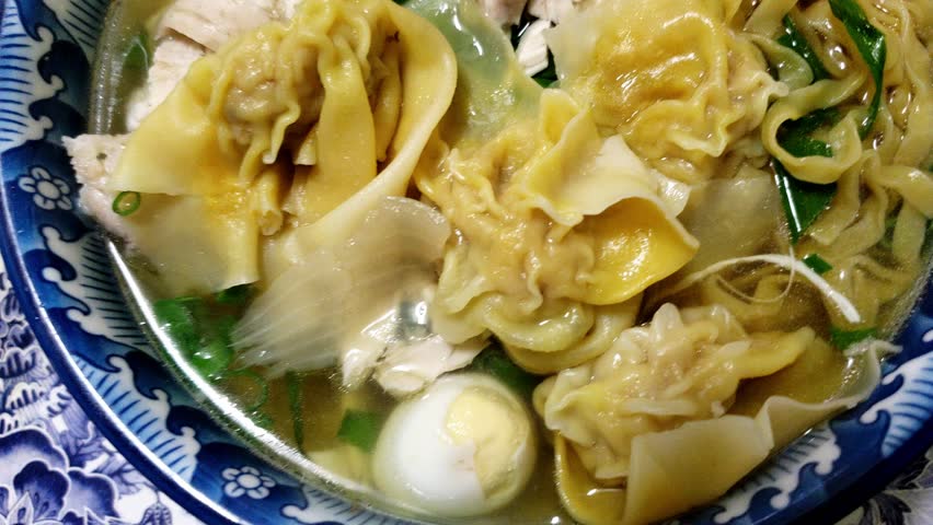 Chinese Dumpling (Wonton) and Egg Noodle Soup. Garnished with lean white chicken meat and vegetable. Close-up view. 4k24.