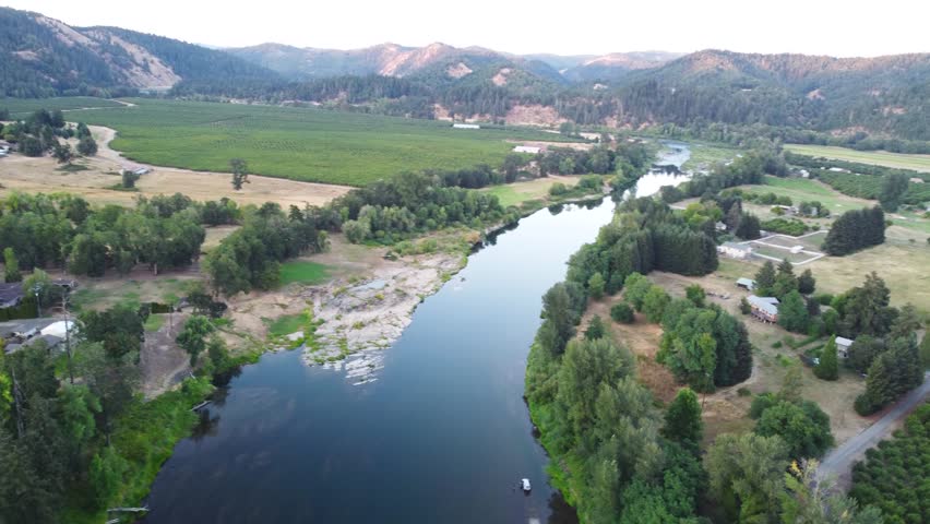 Water Flowing Down Lush Oregon River at Sunset. Main Umpqua River, Roseburg. Summer Low Water Line Showing Green Islands and Vibrant Forests. Slow Calm Reflective Water, Push Forward