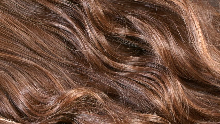 Close-up brown curly hair texture, female long hair background in slow motion