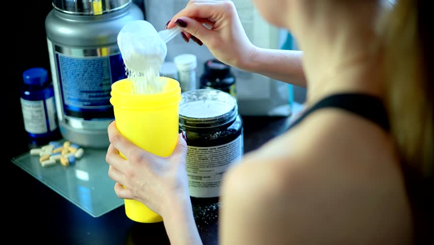 fit woman preparing sport nutrition. woman in sportswear making her protein shake after a workout at home. Drink supplements high-nutrition drinks, diet and muscle-building. preparing protein cocktail
