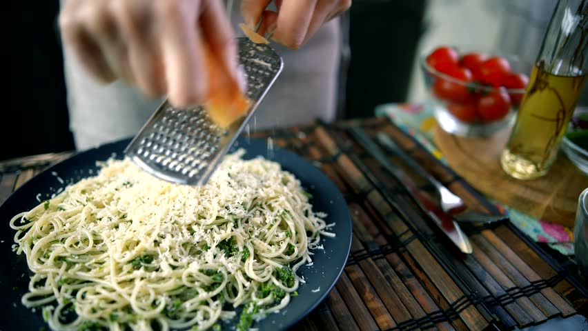 Chef grates hard cheese on top of a freshly prepared pasta dish, Pasta is Mediterranean Italian traditional cuisine. Restaurant Culinary Italian Food. grating parmesan cheese onto delicious pasta
