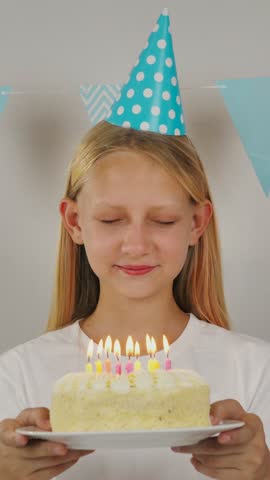 Girl blows out candles on cake.