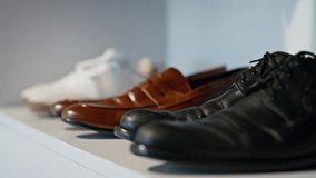 Leather shoes standing shelf in rich person wardrobe closeup. Different colours male footwear placed white modern closet. Three pairs of elegant luxury boots in store. Business people fashion concept - Powered by Shutterstock - Get 15% off with code: PIKWIZARD15