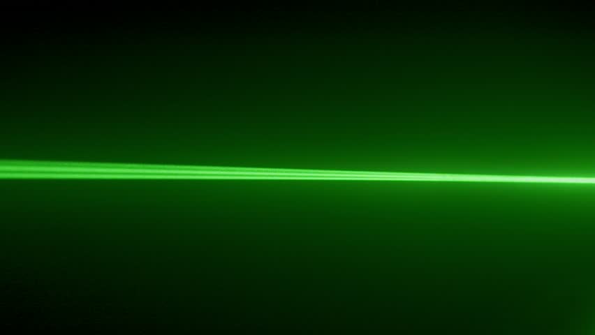 Spinning flashing green laser light beam flashing in darkness, colorful light ray projector shining through smoky air, isolated on black background.