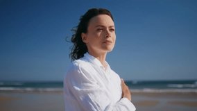 Contemplative woman standing beach enjoying summer breeze closeup. Thoughtful lady wearing white shirt relaxing at sunny seashore. Portrait relaxed brunette contemplating ocean view feeling alone. - Powered by Shutterstock - Get 15% off with code: PIKWIZARD15
