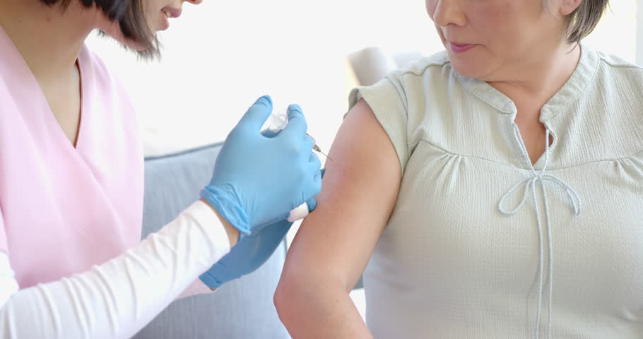 Administering vaccine, healthcare worker giving injection to senior asian woman at home. Vaccination, immunization, elderly, nurse, medicine, homecare