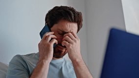 Sad brunette talking smartphone at home closeup. Tired businessman rubbing eyes discussing work problems by mobile phone call at apartment. Worried man speaking cellphone reacting bad news at house - Powered by Shutterstock - Get 15% off with code: PIKWIZARD15