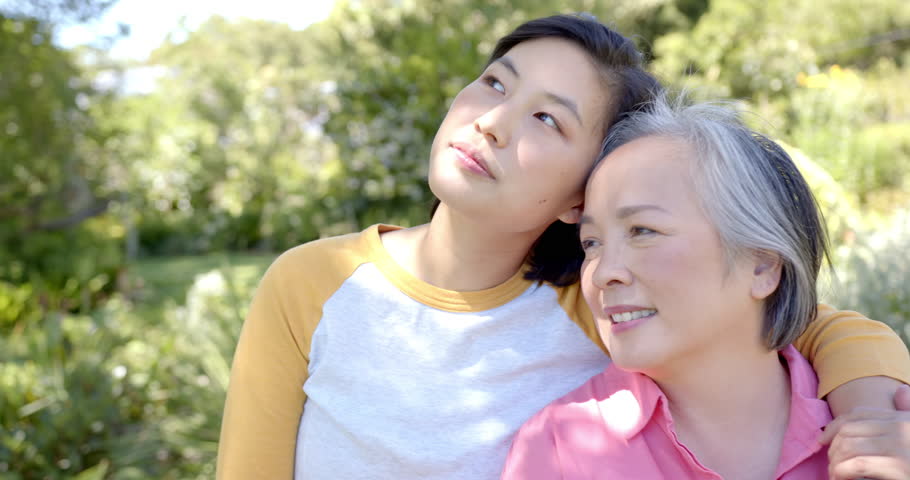 Smiling asian woman embracing elderly asian woman outdoors, enjoying quality time together. Family, bonding, happiness, multigenerational, togetherness, connection