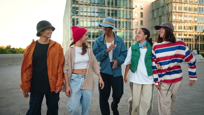 Group of trendy generation Z young friends walking and chatting together in the city. Urban Diversity