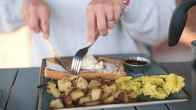 Enjoying a Hearty Breakfast with French Toast Sides person cutting into French toast topped with whipped cream, served with scrambled eggs, roasted potatoes, jam cozy breakfast setting French toast - Powered by Shutterstock - Get 15% off with code: PIKWIZARD15