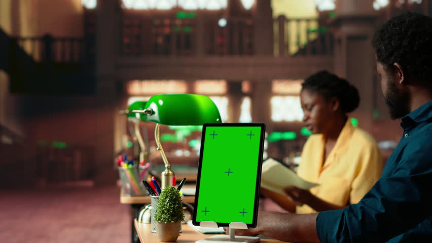 African american team studying for exams next to chroma key display, reading important information from copy books. Young university students use learning tools from database. Camera B.