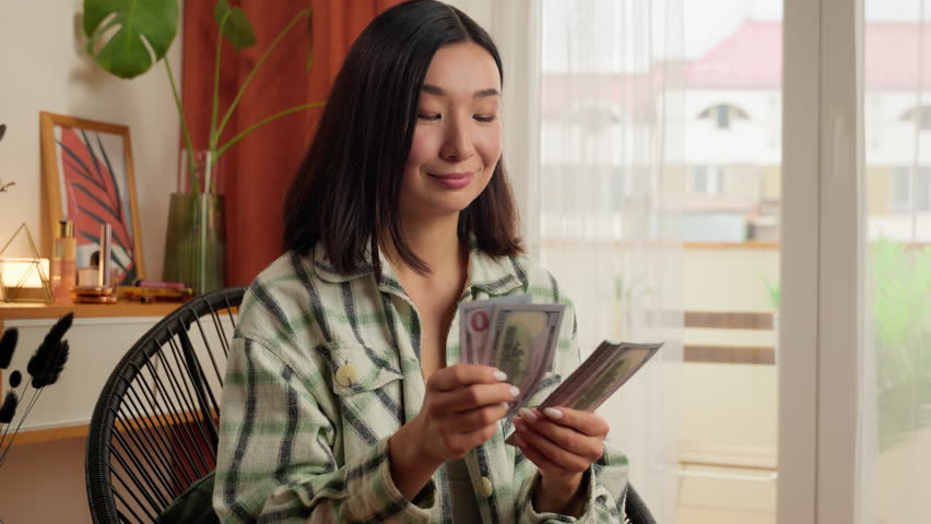 Happy Asian Korean woman female counting money bills finance homeowner tenant home girl smiling rich lady successful businesswoman business dollars banknotes cash salary budget win lottery rent indoor