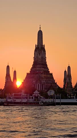 As the sun sets behind the majestic Wat Arun Bangkok, the sky glows with warm hues, illuminating the intricate architecture of this iconic temple