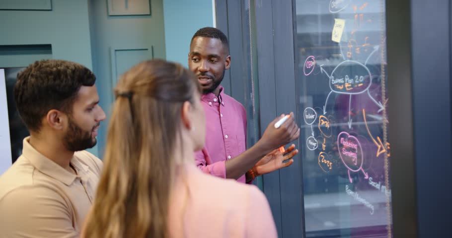 Discussing business strategy, team brainstorming ideas on glass board in office. teamwork, collaboration, planning, innovation