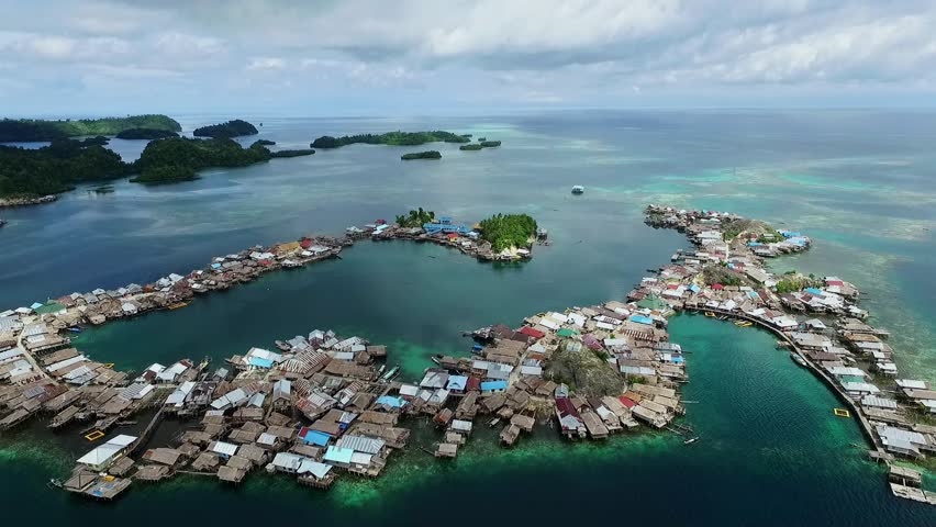 Togean Islands, Central Sulawesi, Indonesia - September 2017: Beautyful aerial view of sea gypsy houses "bajau trible village". natural blue water, white sand and coral reefs surround their homes