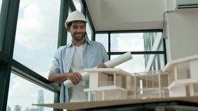 Professional architect engineer walking while looking at skyscraper view. Skilled project manager holding project plan while looking at window with house model placed on table. Design. Tracery - Powered by Shutterstock - Get 15% off with code: PIKWIZARD15