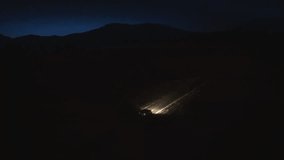 Car riding through winter forest road at night aerial tracking shot. Vehicle illuminated with headlights driving in countryside in evening drone view - Powered by Shutterstock - Get 15% off with code: PIKWIZARD15