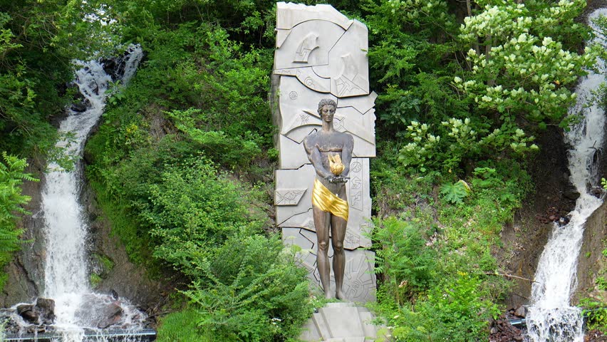 Monument to Prometheus at waterfall in Borjomi, Georgia. depicts statue of god, surrounded by lush vegetation