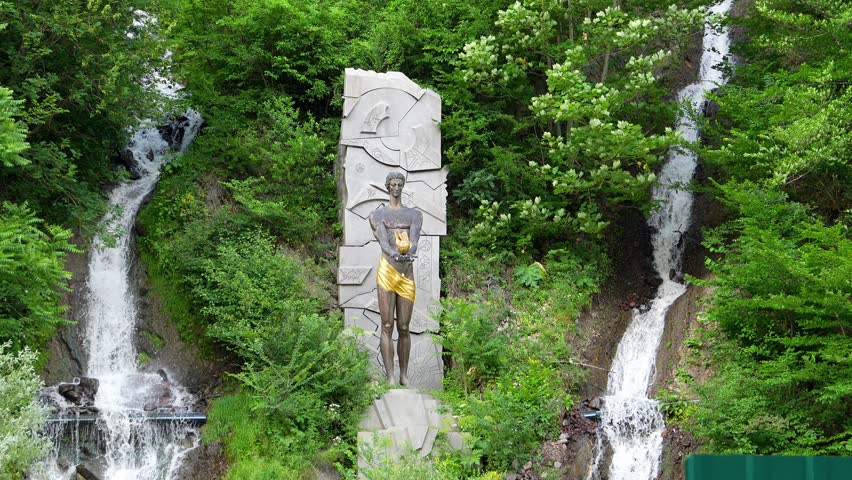 Monument to Prometheus at waterfall in Borjomi, Georgia. depicts statue of god, surrounded by lush vegetation