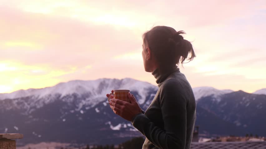 Woman with coffee and mountain view. Concept: relaxation and travel. Soft, warm lighting.	