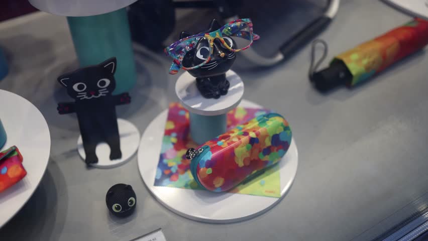A charming display in a toy store featuring black cat-themed accessories, including a figurine wearing colorful glasses and a matching case. The playful design sparks joy and creativity for both child
