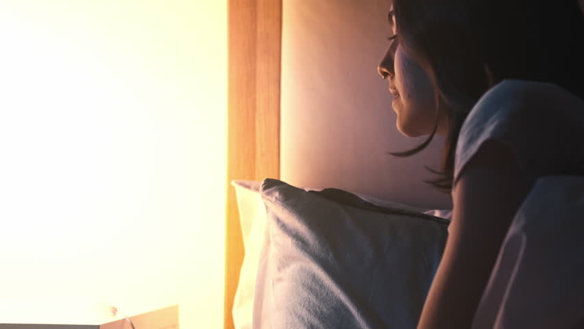 Good night. Home rest. Sweet dreams. Peaceful relaxed woman switching off lamp light lying in cozy soft bed late in dark bedroom.