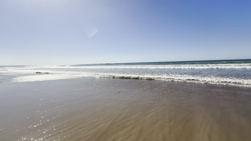 Agadir beach in Morocco in the empty winter sunny months, low tide long slow waves. Clear blue sunny sky with no clouds in sight