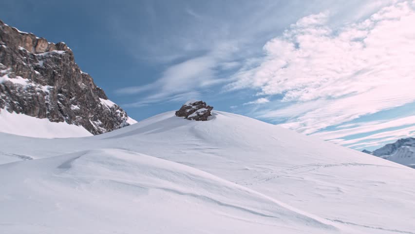Off Piste Snowboarder Jumping. Super Slow Motion, 1000 fps. Snowboarding on Free Ride off Piste Slope on Sunny Day With Clear Blue Sky in European Alps Mountains, Austria. Speed Ramp Effect.
