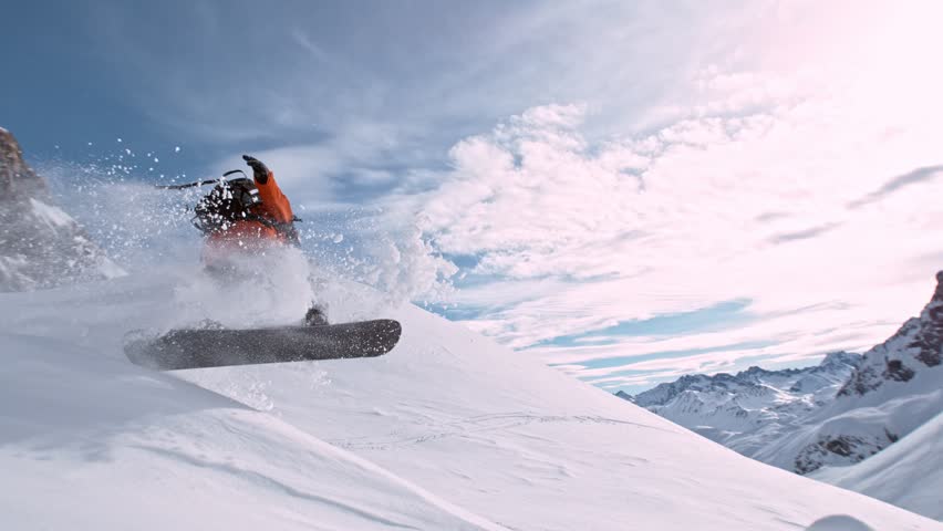 Off Piste Snowboarder Jumping. Super Slow Motion, 1000 fps. Snowboarding on Free Ride off Piste Slope on Sunny Day With Clear Blue Sky in European Alps Mountains, Austria. Speed Ramp Effect.