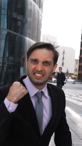 Slow motion. Young attractive businessman enjoy and exult of winning deal with fist shaking outdoor. Glass building district bg. Tie formal suit rapidly shot at sunny afternoon. Smile and happines