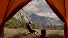 Breathtaking beauty of Yosemite National Park while male hiker camping with beautiful view. Next to his tent tent, enjoy stunning and impressive views of El Capitan and Half Dome - Powered by Shutterstock - Get 15% off with code: PIKWIZARD15