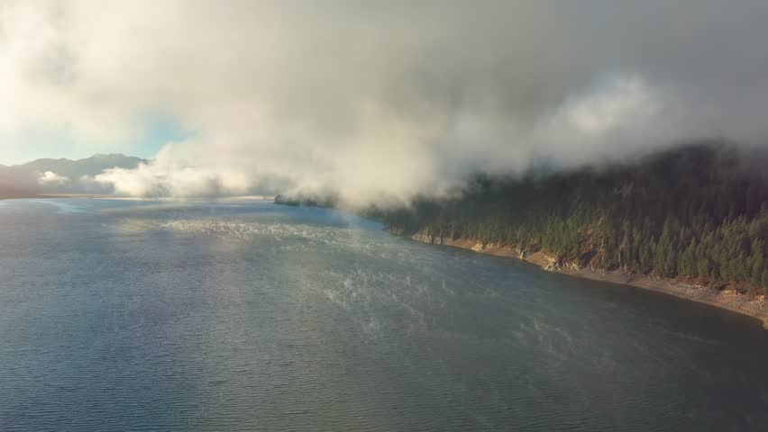 Aerial of low clouds above the Palisades Reservoir on the Snake River in Idaho. Mist if coming off the water.