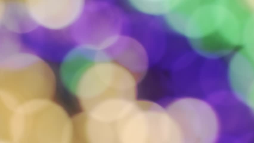 Bokeh of Mardi Gras beads in yellow or gold green and purple. Celebrating Mardi Gras, aka Fat Tuesday. Mardi Gra background in traditional colors.