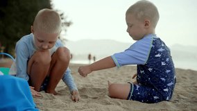 Young brothers wearing protective swimwear bonding while playing together on sandy beach, creating shared moments of childhood joy and carefree exploration under bright sunlight - Powered by Shutterstock - Get 15% off with code: PIKWIZARD15