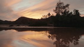 Tranquil Moroccan oasis at sunset. Ripples in water reflect colorful clouds, mountains, and palm trees. Serene nature and beautiful landscape. Perfect for travel, documentary, or relaxation projects. - Powered by Shutterstock - Get 15% off with code: PIKWIZARD15