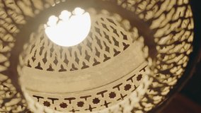 Close-up of an ornate Moroccan lamp. The light illuminates intricate patterns and designs, creating a warm and inviting ambiance. This traditional lamp adds a touch of Moroccan culture. Ornate Lamp - Powered by Shutterstock - Get 15% off with code: PIKWIZARD15
