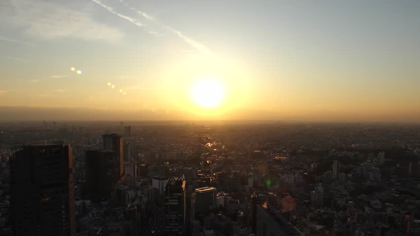 TOKYO, JAPAN : Aerial high angle sunset view of CITYSCAPE of TOKYO. Dramatic clouds and buildings around Shibuya. Japanese urban city life and metropolis concept. 4K time lapse shot, dusk to night.