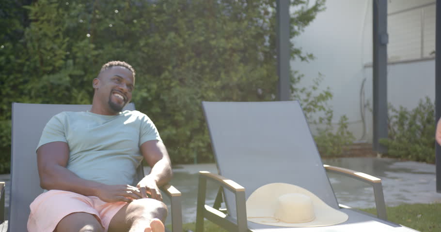 Relaxing on lounge chair in backyard, man enjoying sunny day outdoors. Relaxation, leisure, sunshine, comfort, summer, lounging