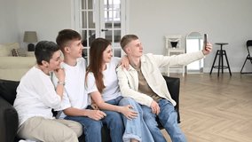 Family of four people sitting on sofa together at home and taking selfie photo on smartphone. People posing for funny photo or recording video blog on phone enjoy weekend together. - Powered by Shutterstock - Get 15% off with code: PIKWIZARD15