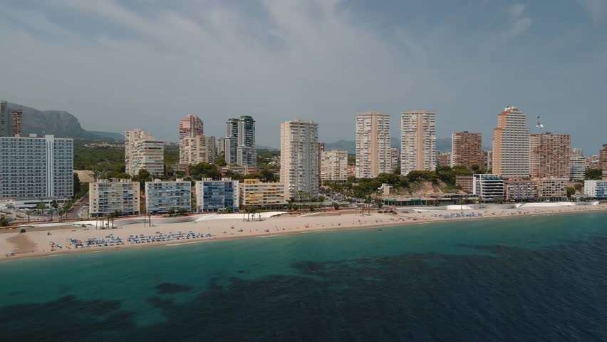 Aerial drone footage of Benidorm, Spain. Skyscrapers, view of Intempo Building and surrounding urban landscape, sandy long beach, coastline, resting tourists, Mediterranean Sea in summer days