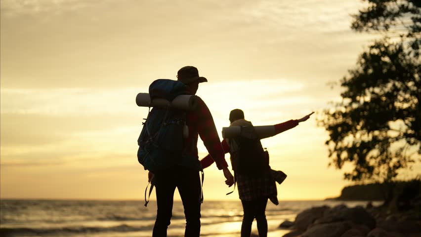 Active lifestyle, young people dancing in nature, backpackers have fun. Beautiful landscape on coastline in sunset, hikers admiring seascape and horizon, good mood and positive emotions, slow motion