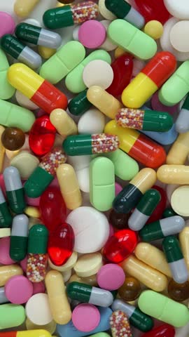 Top view of colored medical pills rotate in circle. Pills and drugs tablets. Pharmaceutical Industry. Medicine concept. Health care. Vertical shot