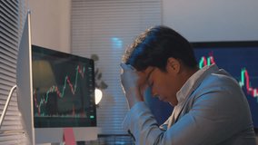Montage of a worried businessman sitting at his desk and looking at computer screens showing a falling stock market chart, touching his head with his hands - Powered by Shutterstock - Get 15% off with code: PIKWIZARD15