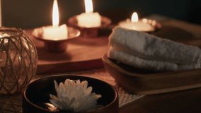 Close-up rack focus view of composition of three candle holders with burning candles, white flower and towel conveying relaxed atmosphere in spa room - Powered by Shutterstock - Get 15% off with code: PIKWIZARD15