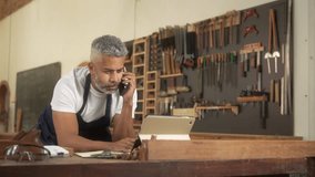 Focused entrepreneur multitasking between phone call, laptop, and paperwork. Dedicated business owner managing tasks with focus and efficiency in a workshop setting - Powered by Shutterstock - Get 15% off with code: PIKWIZARD15