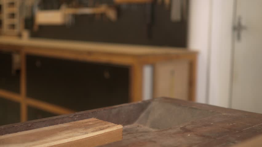 Carpenter measuring wooden plank and marking it with a pencil in workshop. Hands of a craftsman using tape measure on wood while working on precision task